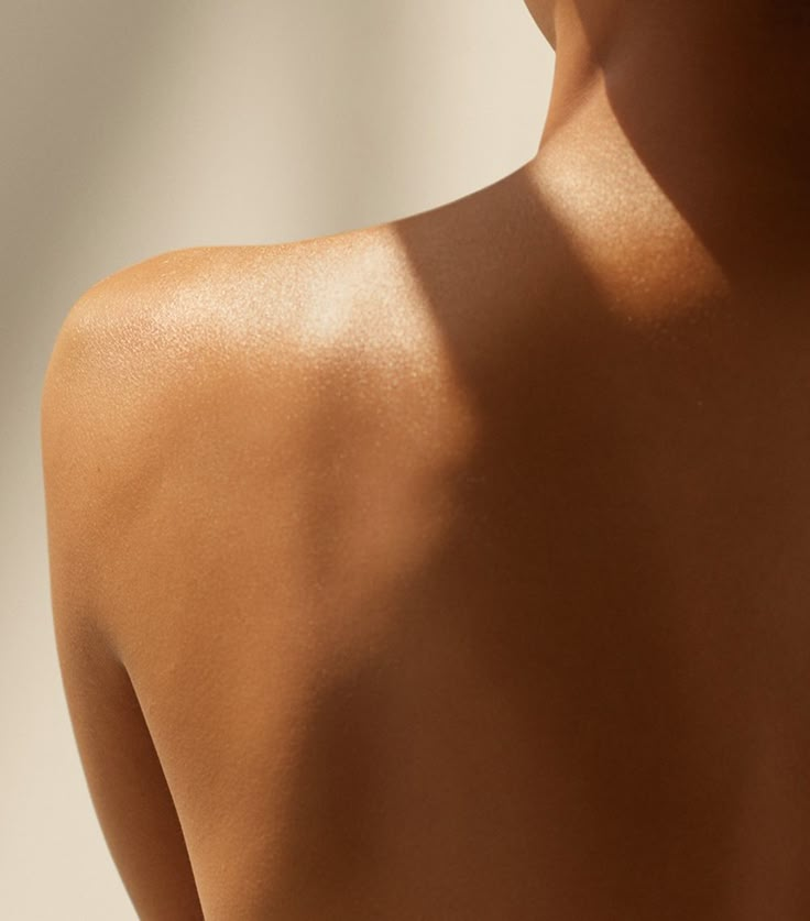 Close-up of a person's bare back and shoulder, with light and shadow patterns across the skin.