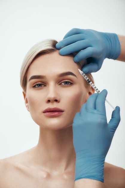 Person receiving an injection in the forehead from a gloved professional.